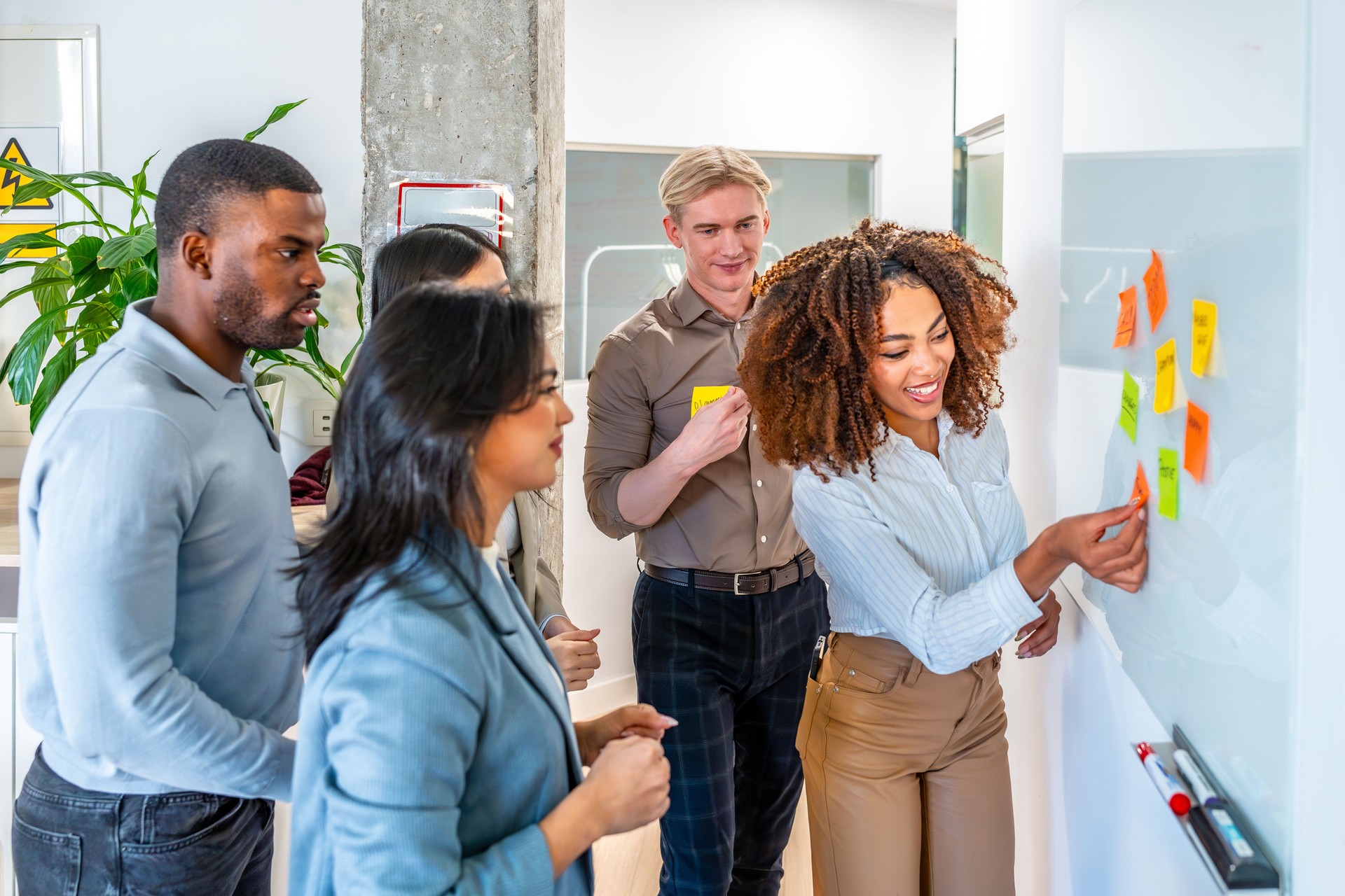 Coworkers using sticky notes on whiteboard during meeting in office